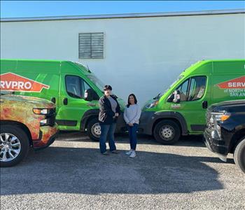 Two women standing in front of SERVPRO vehicles