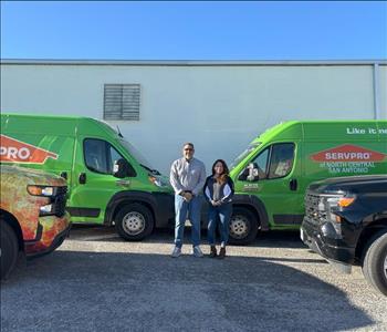 Man and Woman Standing in front of SERVPRO trucks